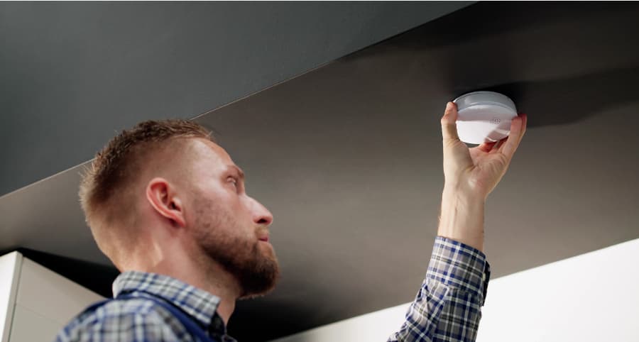 Man placing a smoke detector inside a home